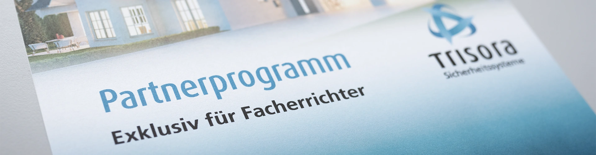 Schriftzug "Partner-Programm – Exklusiv für Facherrichter" und Trisora Logo mit stimmungsvollem Ausschnitt eine Hauses im Hintergrund